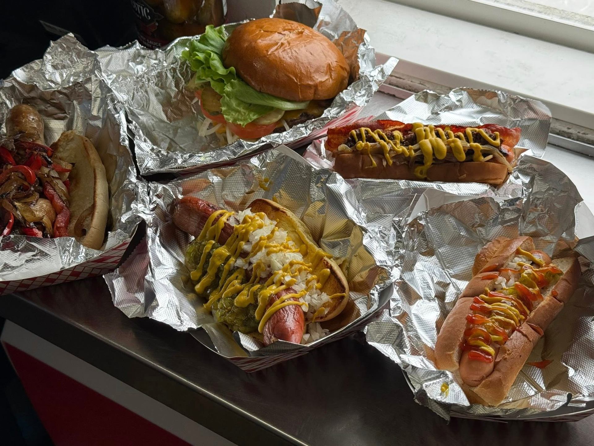 A spread of grilled Kayem dogs, a sausage hoagie and a steakhouse burger from Zippity Do Dog